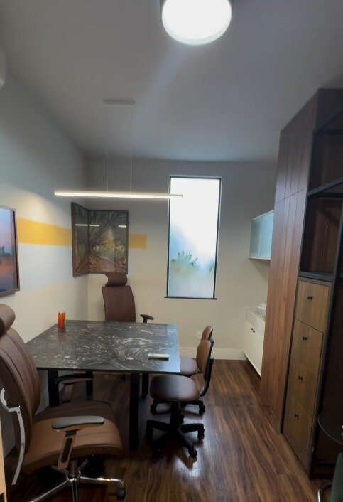 Sala de reunião do escritório, com mesa de pedra escura e cadeiras